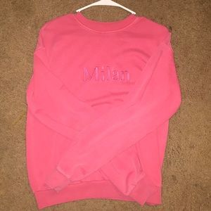 a pink sweatshirt , with the words Milan on it.